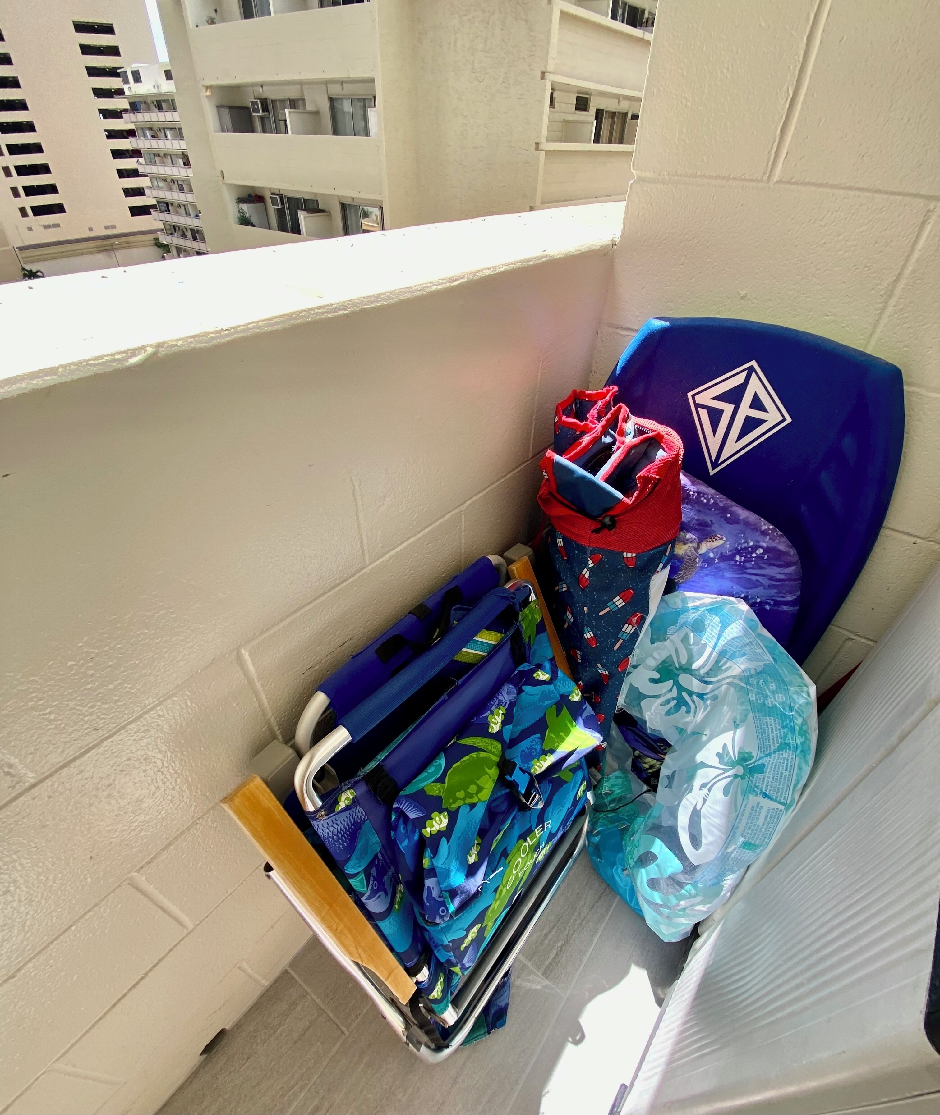 A balcony with a luggage rack holding several bags, including a blue bag with a space-themed design and a red bag with a geometric pattern.