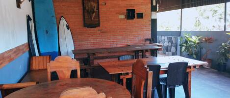 Un área de comedor al aire libre con paredes de ladrillo, mesas y sillas de madera.