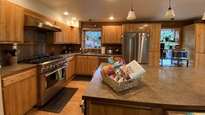 A modern kitchen with wooden cabinets, stainless steel appliances, and pendant lighting. - The Best Kenai Peninsula Base Camp. (Sterling)