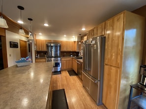 A modern kitchen with wooden cabinets, stainless steel appliances, and a large island.