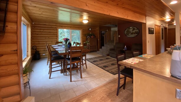 A wooden cabin interior with a dining area, kitchen, and living space. - The Best Kenai Peninsula Base Camp. (Sterling)