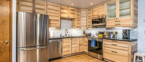 A modern kitchen with wooden cabinets, stainless steel appliances, and a tiled backsplash.