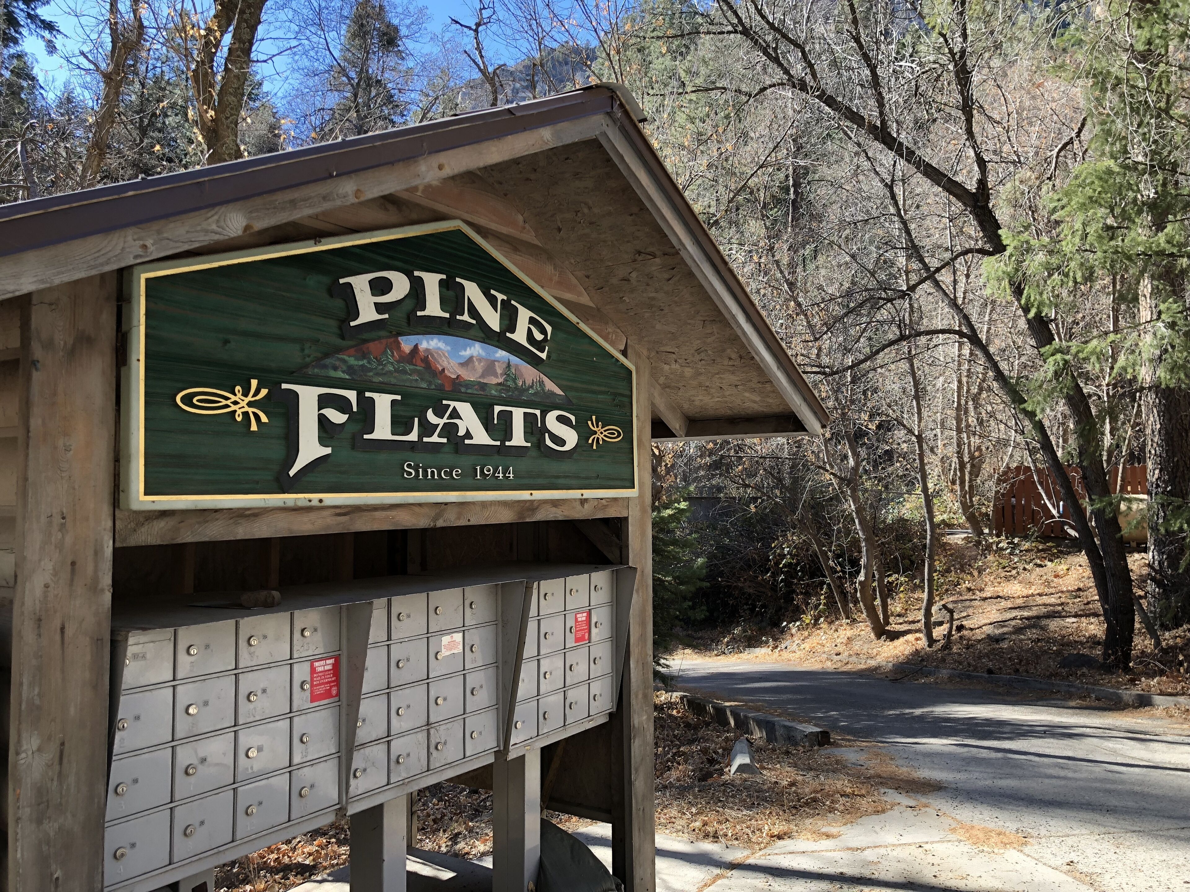 Un bâtiment en bois sur lequel on peut lire l’inscription « Pine Flats, fondé en 1944 », avec une rangée de boîtes aux lettres en dessous.