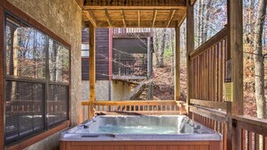 A hot tub in a wooden cabin with a view of the forest. - Lazy Bear Lodge: 6BR, Theater,Spa,Pool,Game room! (Pigeon Forge)