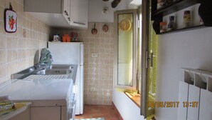 Eine Küche mit Spüle, Schränken und einem Fenster mit Vorhang.