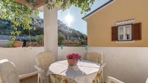 Un patio con una mesa y sillas, una planta en maceta y vistas a edificios y vegetación.