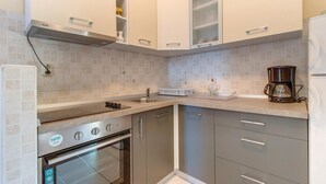 Una cocina compacta con horno integrado, cafetera y lavamanos.