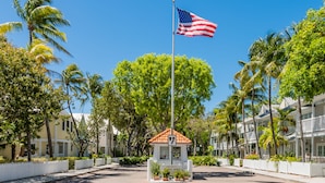 A coastal hotel with a flagpole, a welcome sign, and a white picket fence.