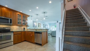 A kitchen with wooden cabinets, stainless steel appliances, and a tiled floor.
