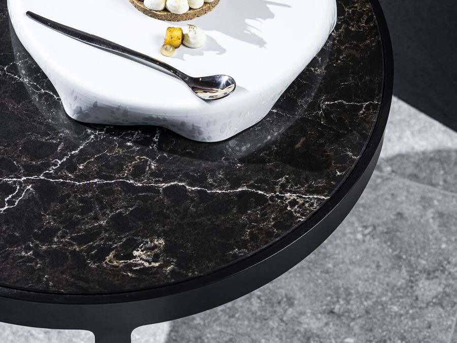 A dessert on a white plate with a spoon, placed on a black marble table.