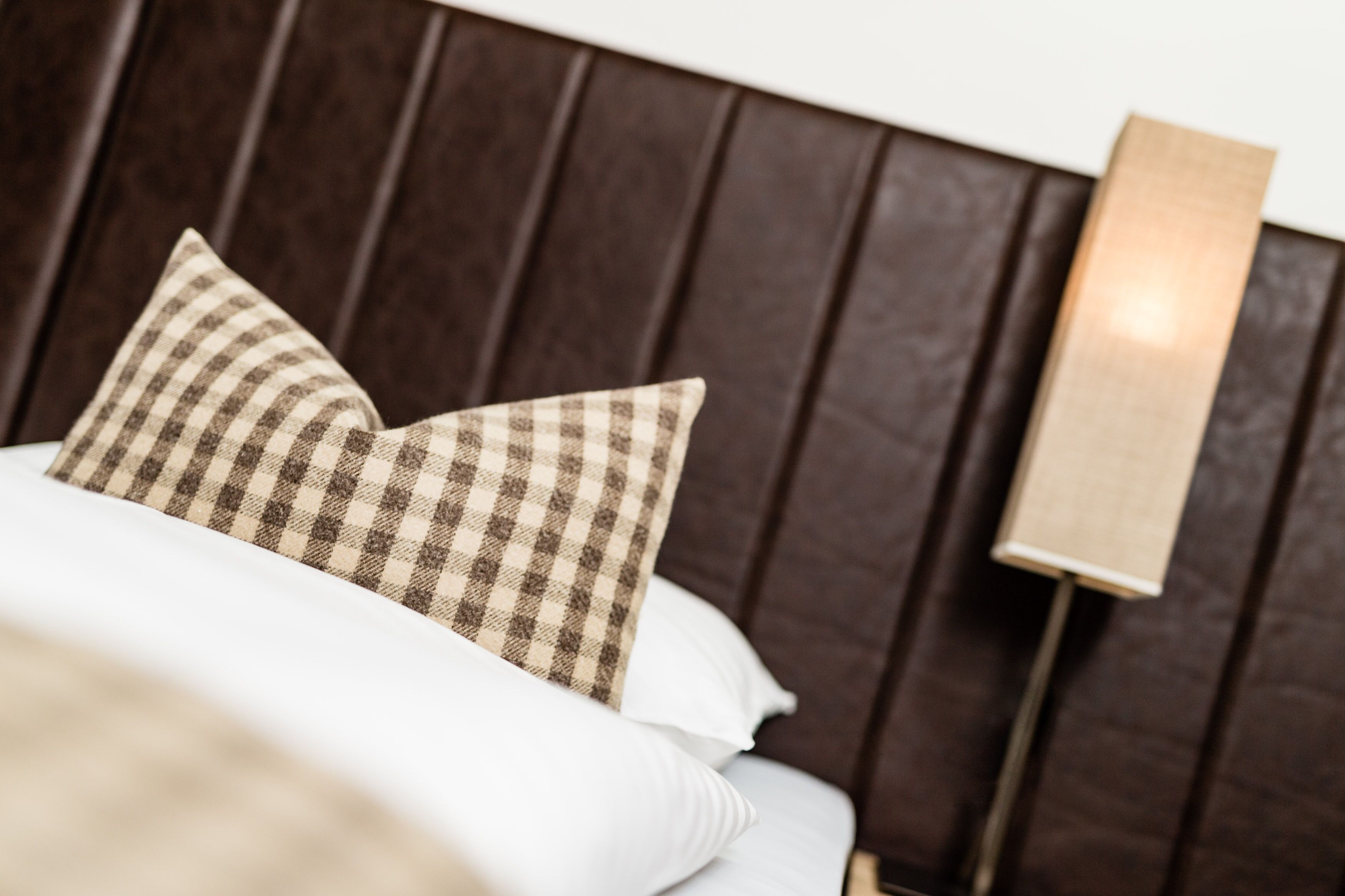 Una cama con almohadones a cuadros y un cabecero de madera.