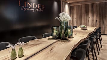 Ein Konferenzraum mit einem langen Holztisch, schwarzen Stühlen und dekorativen Vasen mit Blumen.