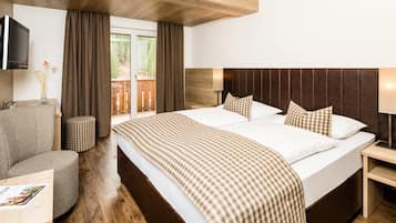 A hotel room with a large bed, a TV mounted on the wall, a wooden headboard, and a view of the outdoors through the window.