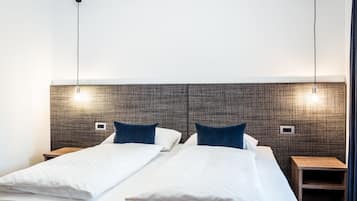 A double bed with white linens and blue pillows, two bedside tables, and a textured headboard.