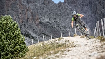 Een mountainbiker op een zandpad met rotsachtige kliffen op de achtergrond.