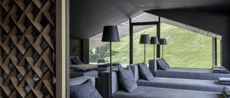 A modern hotel room with a high ceiling, large windows, and a view of the outdoors.