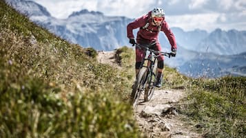 A mountain biker on a dirt trail with a mountainous backdrop.
