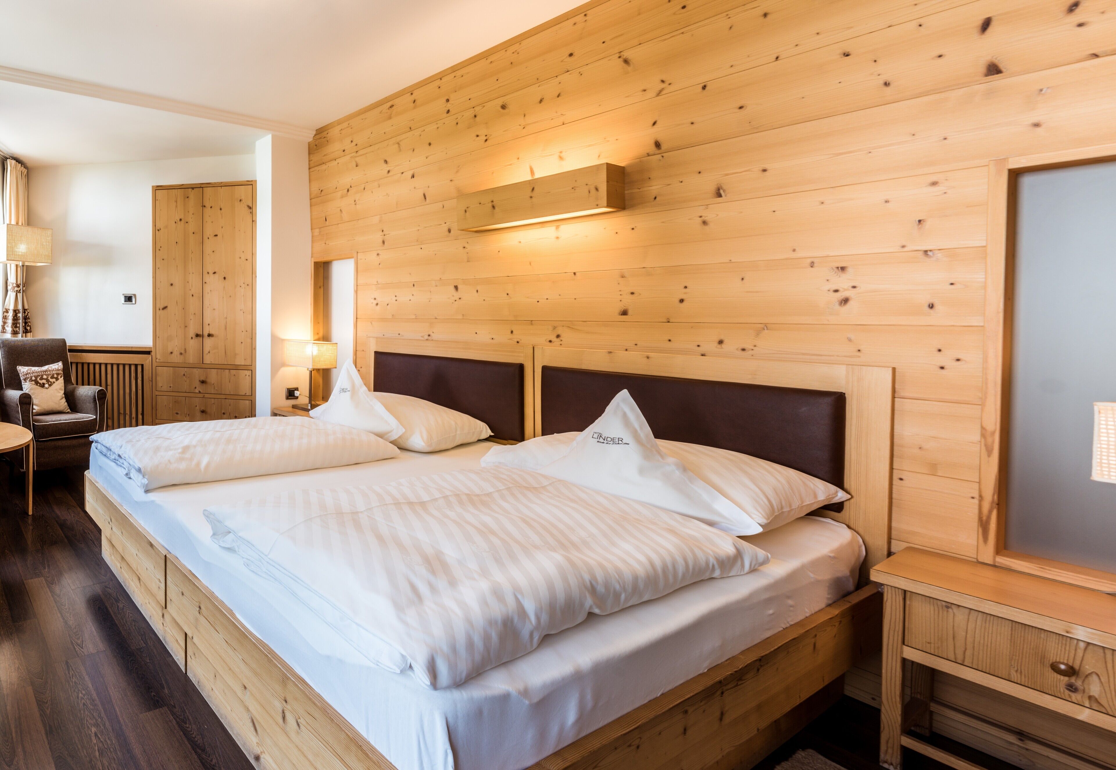 Ein Schlafzimmer mit Holzwänden, einem Doppelbett, Nachttischen und einer Lampe.
