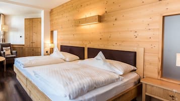 A wooden-paneled bedroom with a double bed, bedside tables, and a lamp.