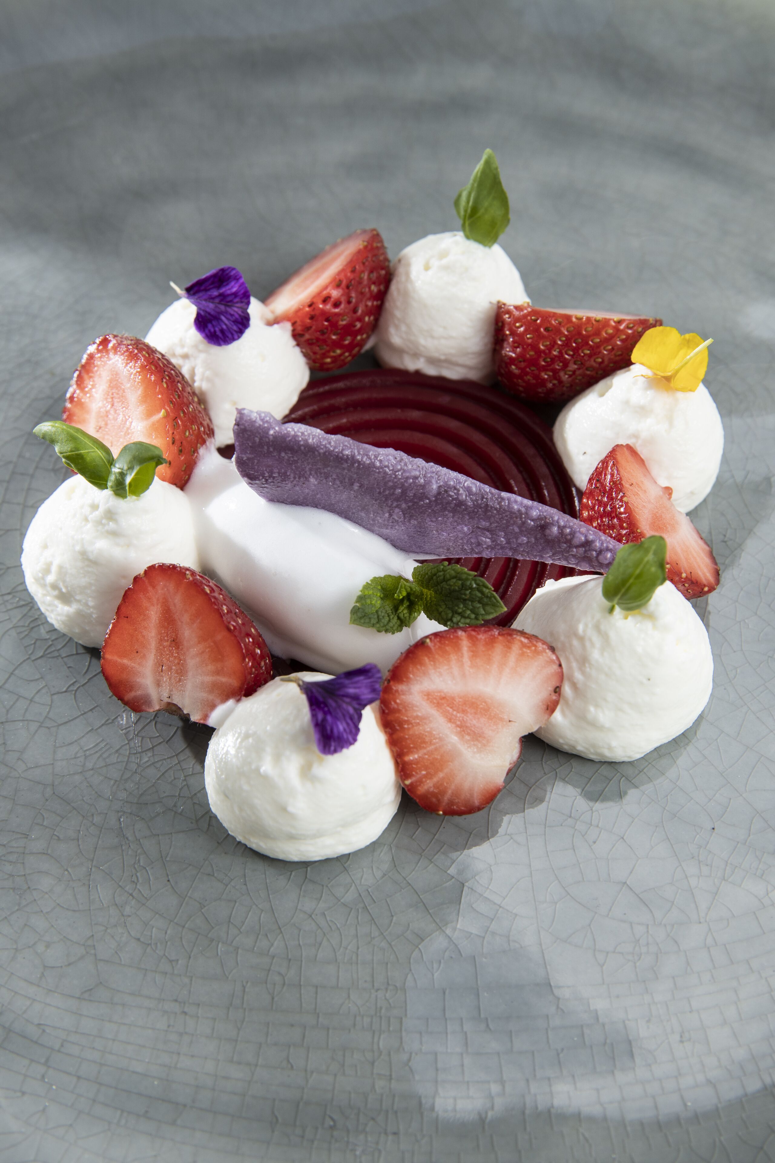 Un dessert aux fraises, avec un objet violet posé sur une surface texturée.