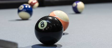 A pool table with billiard balls and a cue stick.