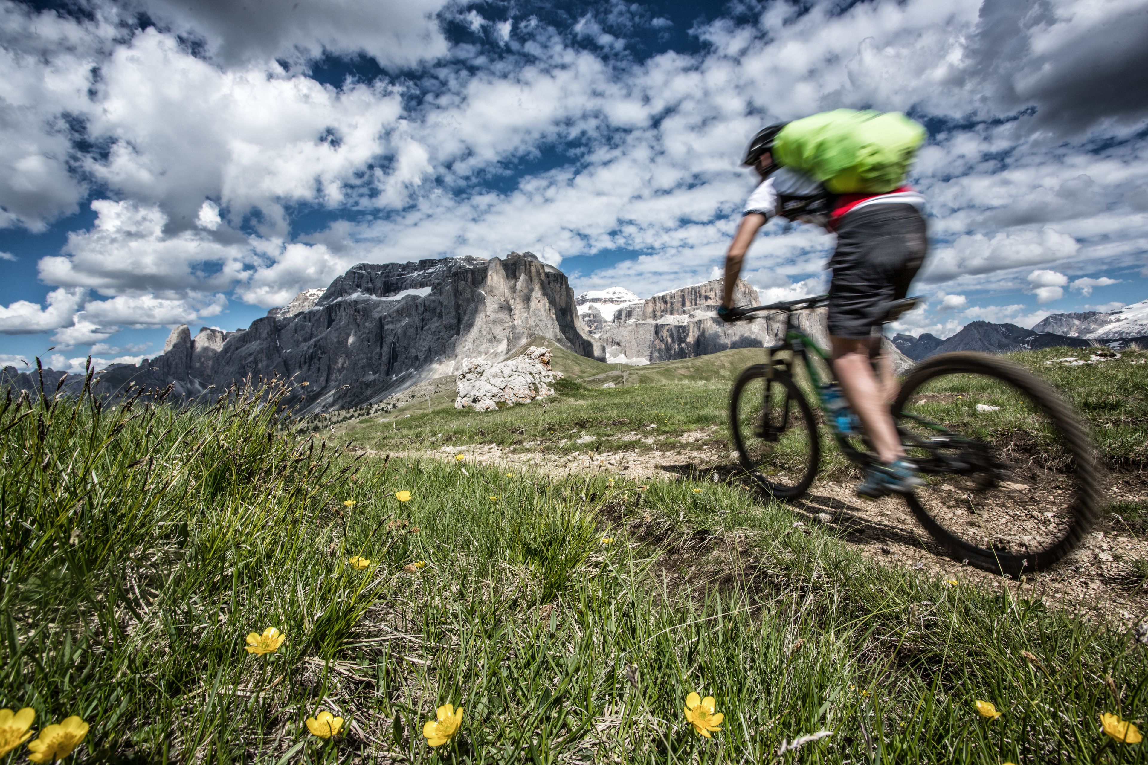 Ein Mountainbiker auf einem Pfad vor einer schroffen Bergkulisse.