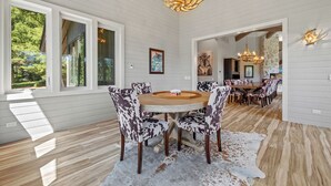 A spacious dining area with a round wooden table and patterned chairs, a chandelier, and a cowhide rug. - RMR: Hal`e Teton Home in Teton Village (Teton Village)