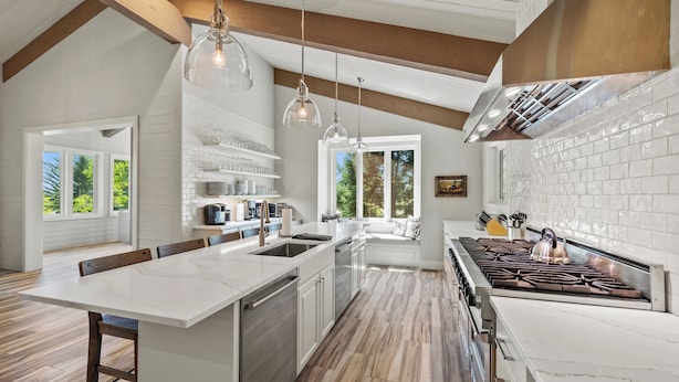 A modern kitchen with a large island, white subway tiles, and a stainless steel stove. - RMR: Hal`e Teton Home in Teton Village (Teton Village)