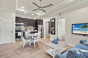 A modern kitchen with dark cabinets, stainless steel appliances, and a dining area with white chairs. - Gulf Waters-Beach Club at Siesta Key 108D by RVA (Sarasota)