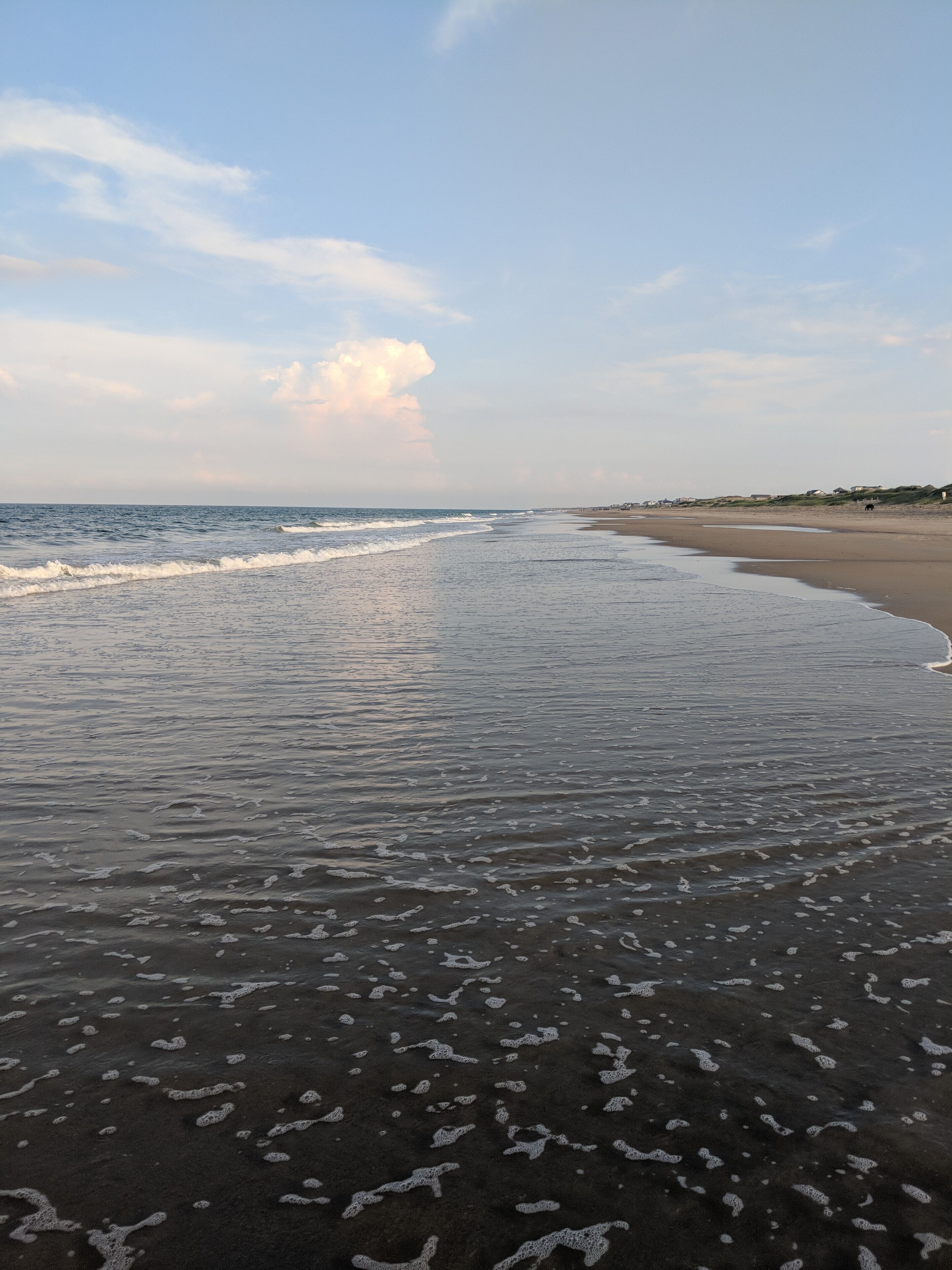 A beach with gentle waves and a clear sky.