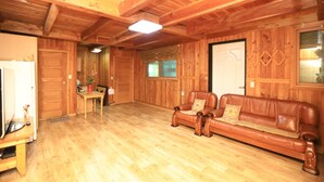 Een houten interieur met een houten vloer, een bruine leren bank, een houten tafel en een deur.