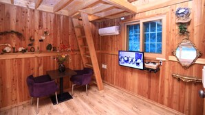Een houten interieur met een eethoek, een televisie en een raam.