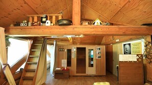 Een gezellig interieur van een blokhut met een hoogslaper, een houten trap, een klein bureau en een raam met gordijnen.