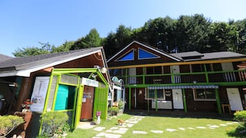 A building with a green and brown facade, a visible entrance, and a stone pathway leading to the entrance.