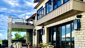 A modern building with a patio area featuring outdoor tables and chairs, a stone facade, and large windows. - PermaVista Ranch & Resort- Experience A Luxury Texas Ranch (Brenham)