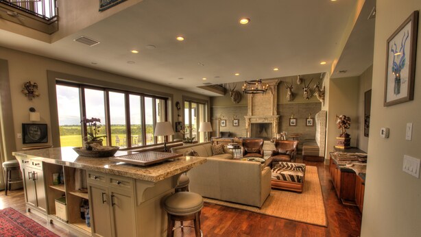 A spacious kitchen with a large island, a fireplace, and a view of the outdoors. - PermaVista Ranch & Resort- Experience A Luxury Texas Ranch (Brenham)