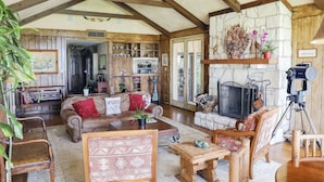 A spacious living room with wooden beams, a stone fireplace, and a variety of seating options. - PermaVista Ranch & Resort- Experience A Luxury Texas Ranch (Brenham)
