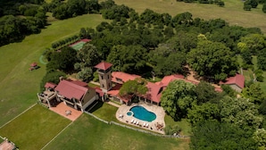 An aerial view of a large estate with multiple buildings, a swimming pool, and extensive greenery. - PermaVista Ranch & Resort- Experience A Luxury Texas Ranch (Brenham)