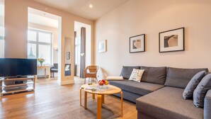 A modern living room with a grey sofa, a wooden coffee table, and a flat-screen TV.