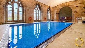A large indoor swimming pool with arched windows and stone walls. - 9 THE MONASTERY WITH LOCH NESS VIEWS - sleeps 4 guests  in 2 bedrooms (Fort Augustus)
