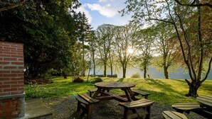 A picnic area with a brick structure, surrounded by trees and a lake view. - 9 THE MONASTERY WITH LOCH NESS VIEWS - sleeps 4 guests  in 2 bedrooms (Fort Augustus)