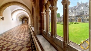 A corridor with arched ceilings and a checkered floor, leading to a building with a stone facade and a lawn. - 9 THE MONASTERY WITH LOCH NESS VIEWS - sleeps 4 guests  in 2 bedrooms (Fort Augustus)