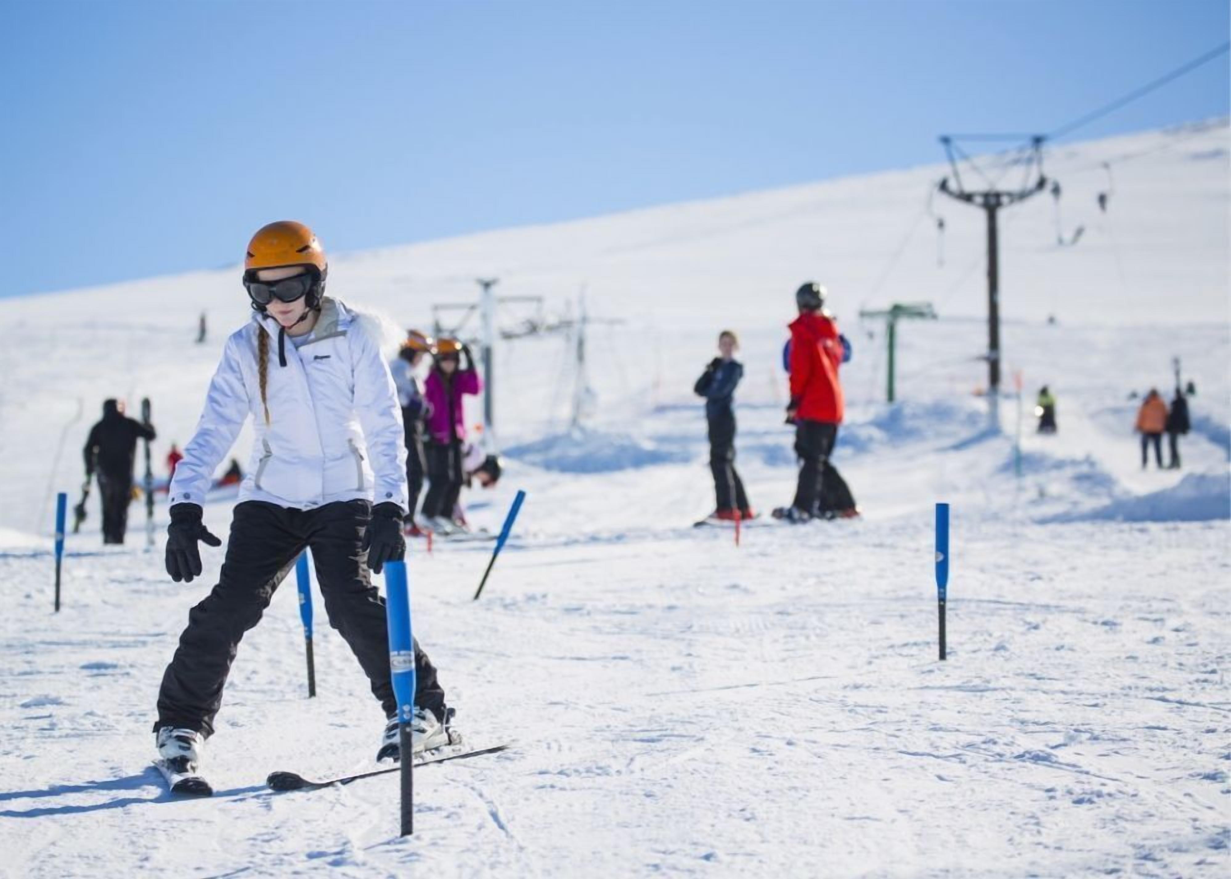 Una persona esquiando en una pendiente nevada con un telesilla al fondo.