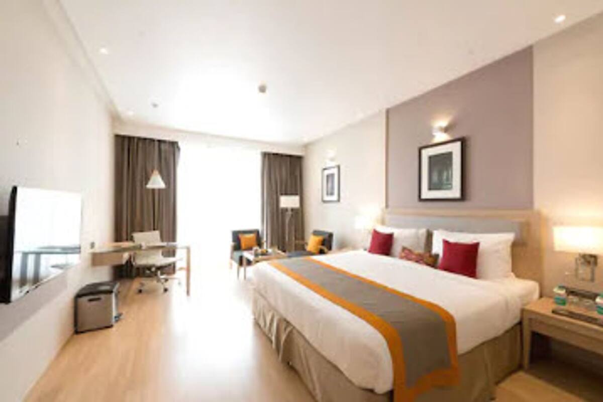 Une chambre d’hôtel avec un grand lit, un bureau, une chaise, une télévision et une fenêtre.