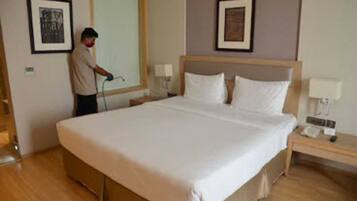 A hotel room with a large bed, a nightstand, a lamp, and two framed pictures on the wall.