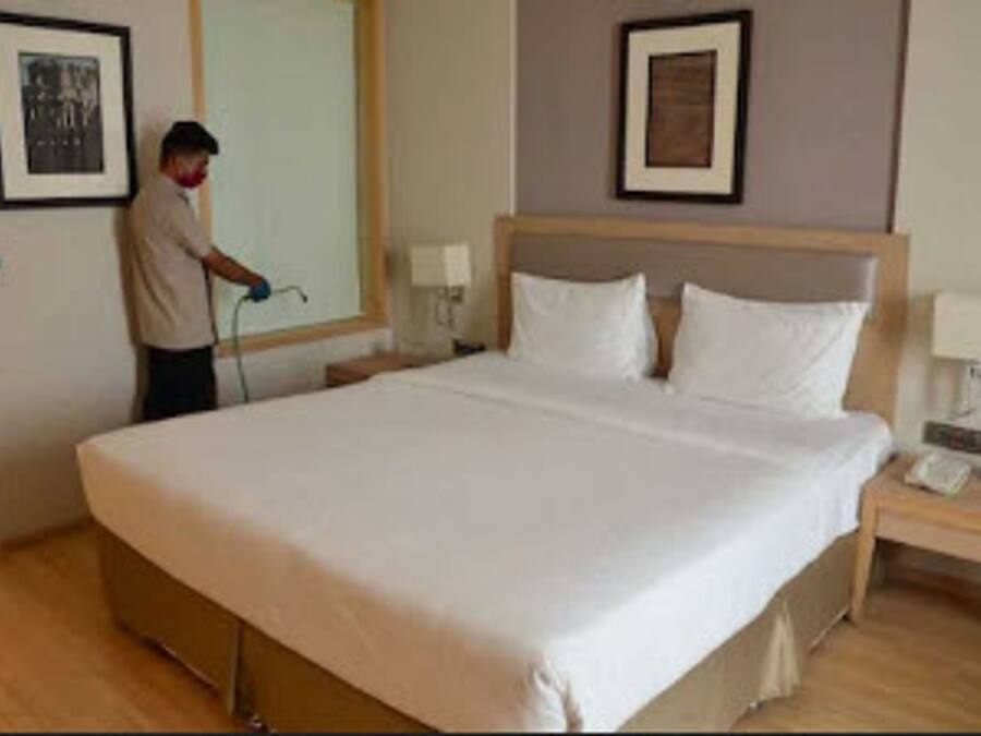 A hotel room with a large bed, a nightstand, a lamp, and two framed pictures on the wall.