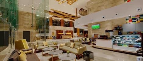 A spacious lobby with modern furniture, a central seating area, and a refreshment bar.