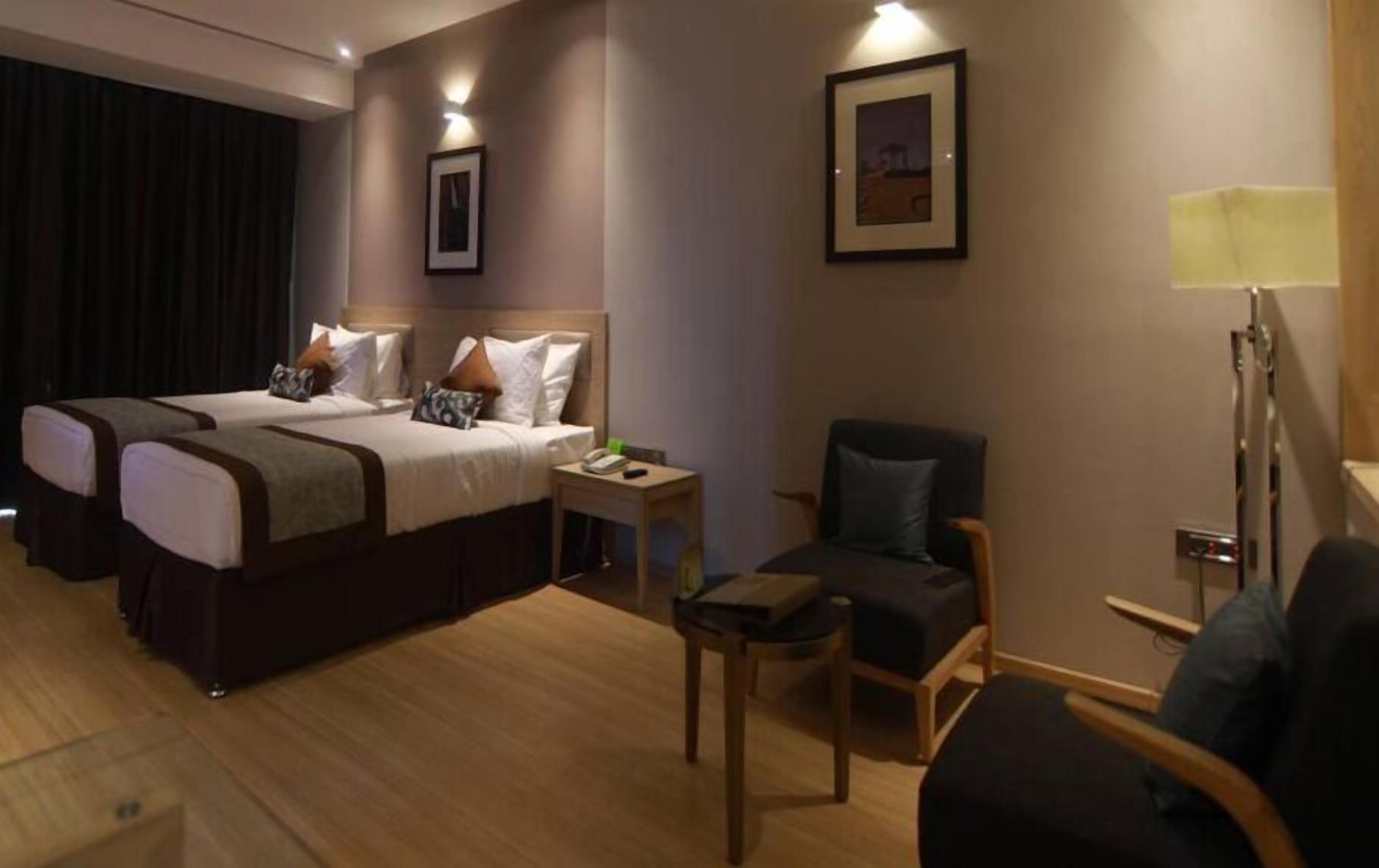 Una habitación de hotel con dos camas, un escritorio, una silla y una mesita de noche.
