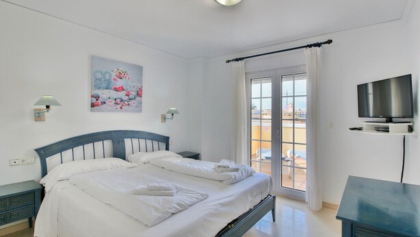 Une chambre d’hôtel avec un lit, une télévision et un balcon offrant une vue.