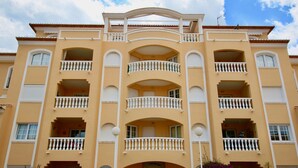 Un immeuble à plusieurs étages, doté de balcons et d’une entrée centrale.